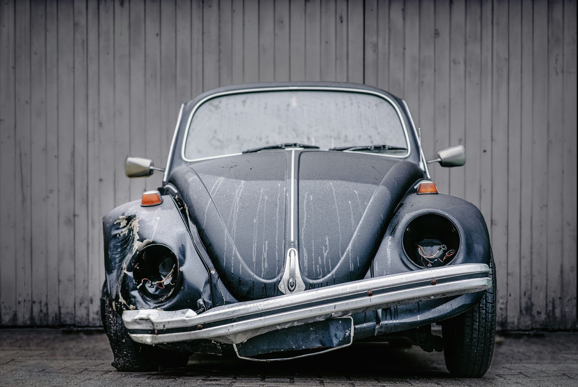 an old vw bug is parked in front of a building