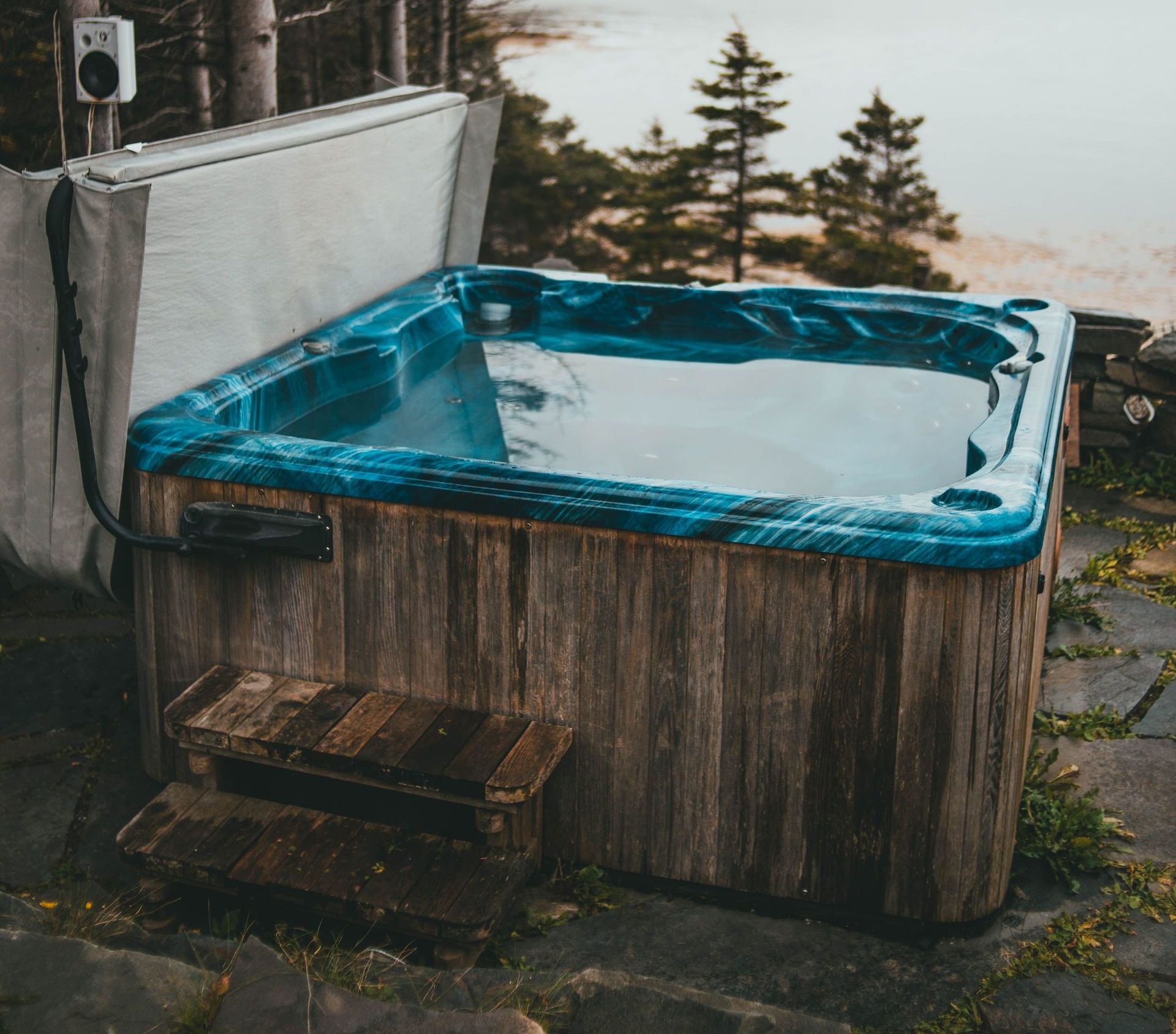 A cozy wooden hot tub in a forest setting with a serene lake view. Perfect for relaxation.